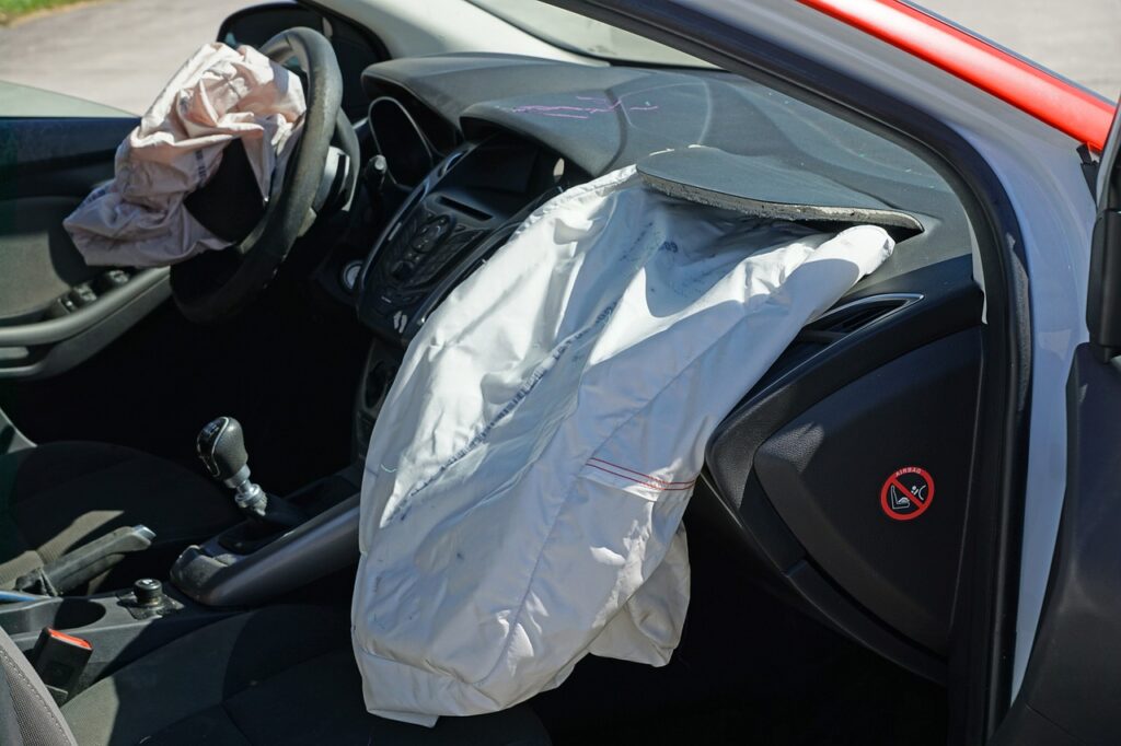 Car airbags deployed after a collision, with the airbags fully inflated inside the vehicle, showing the aftermath of an accident.